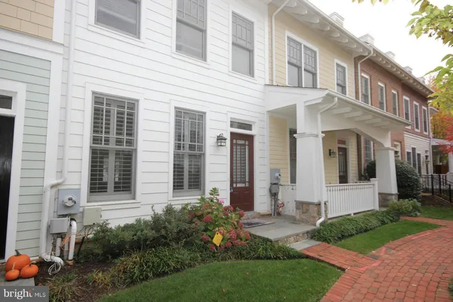 a view of a white house next to a yard and large windows