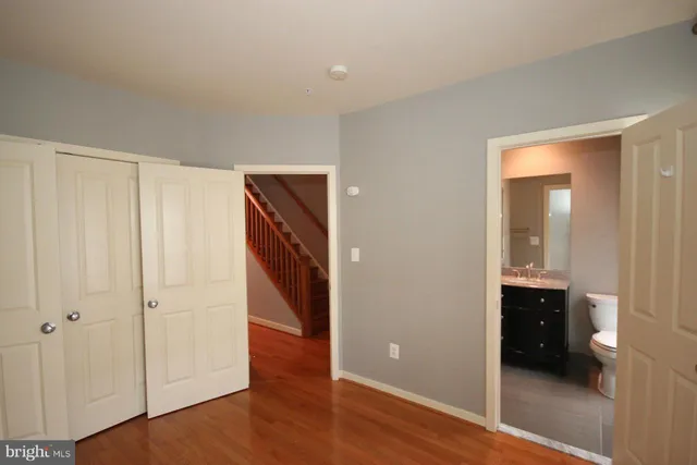 a view of an empty room with wooden floor and closet