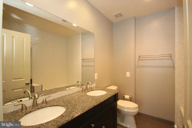 a bathroom with a granite countertop sink toilet and mirror
