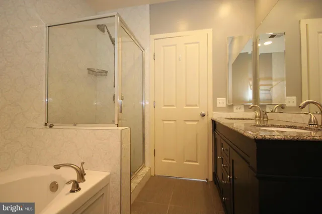 a bathroom with a granite countertop sink a mirror and a bathtub