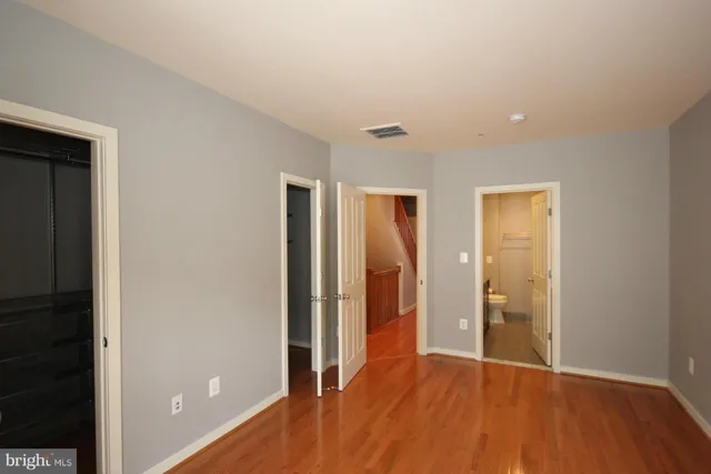 a view of an empty room with wooden floor and closet
