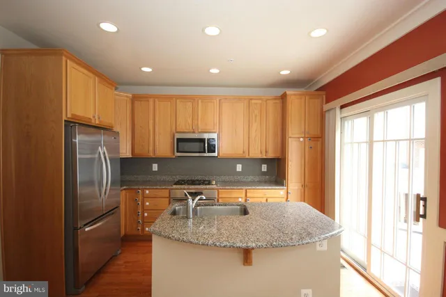 a kitchen with stainless steel appliances granite countertop a sink a stove and a refrigerator
