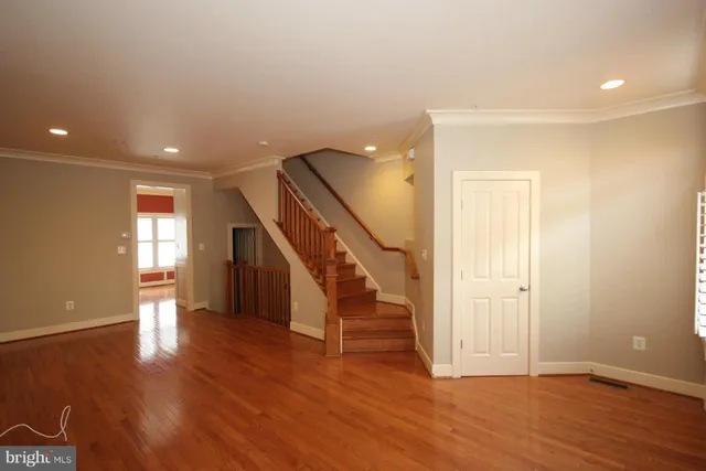 a view of an empty room with wooden floor and stairs