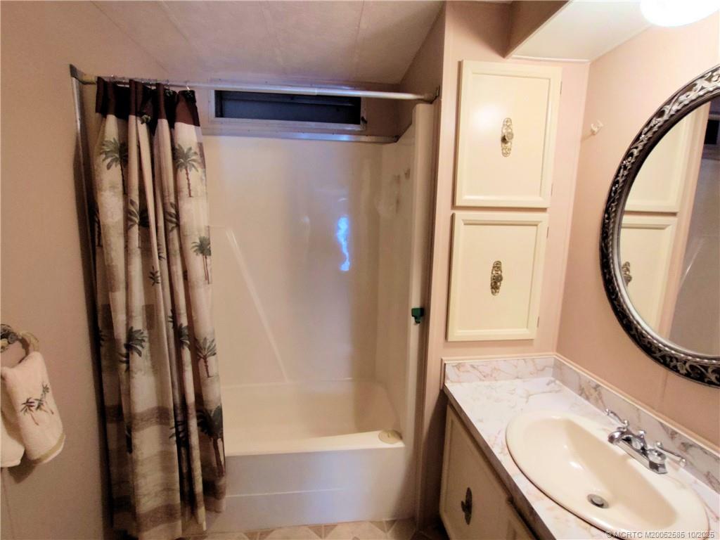 2540 Southeast Penny Lane Stuart, FL 34994 - Photo 37 of 62 a bathroom with a sink a mirror a bathtub and shower
