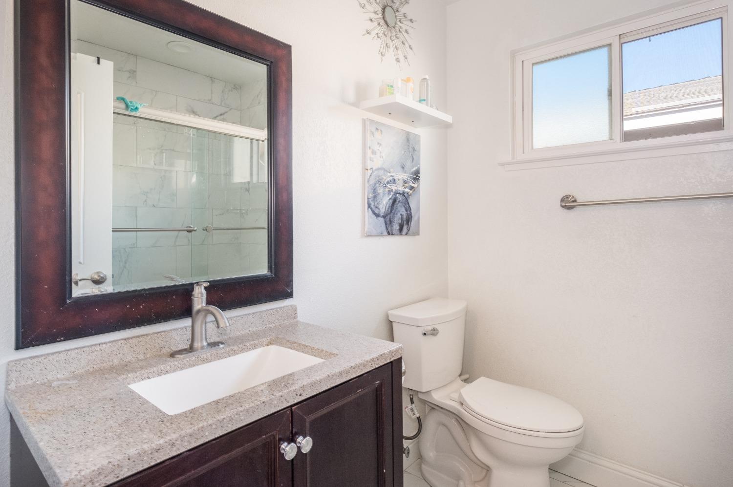 172 West Swift Avenue Clovis, CA 93612 - Photo 15 of 22 a bathroom with a granite countertop sink a toilet and a mirror