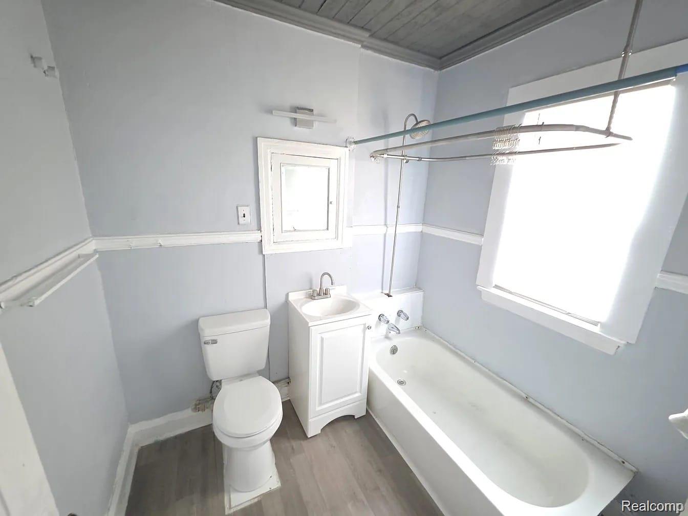 3801 Ellery Street Detroit, MI 48207 - Photo 7 of 8 Bathroom featuring a standard white toilet, a vanity with a white basin and chrome faucet, and a traditional bathtub