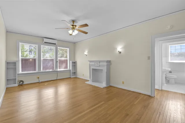 a view of an empty room with a window and wooden floor