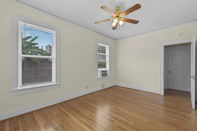 a view of empty room with wooden floor and fan
