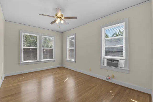 a view of an empty room with a window and wooden floor