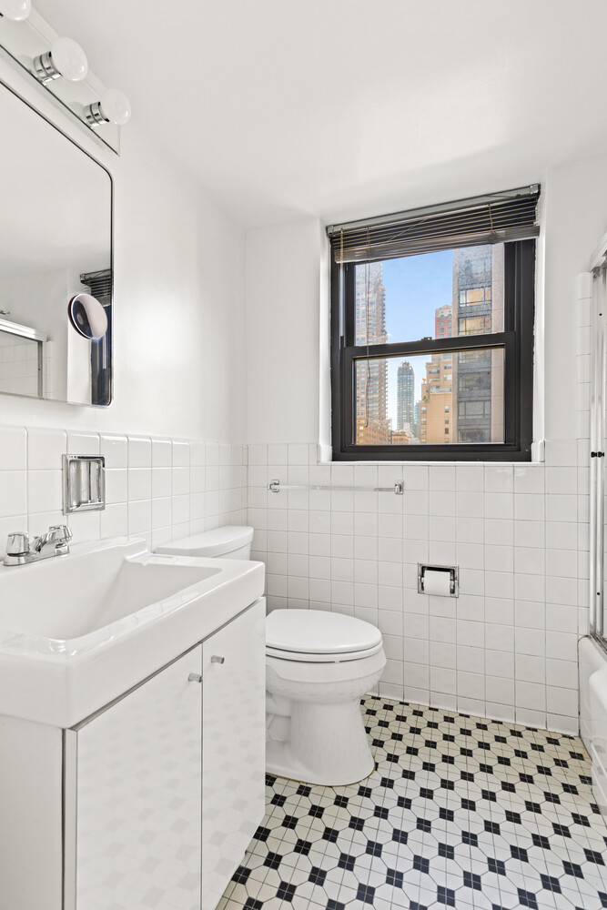 165 East 72nd Street, Unit 11C Manhattan, NY 10021 - Photo 11 of 12 a bathroom with a sink a toilet and a mirror