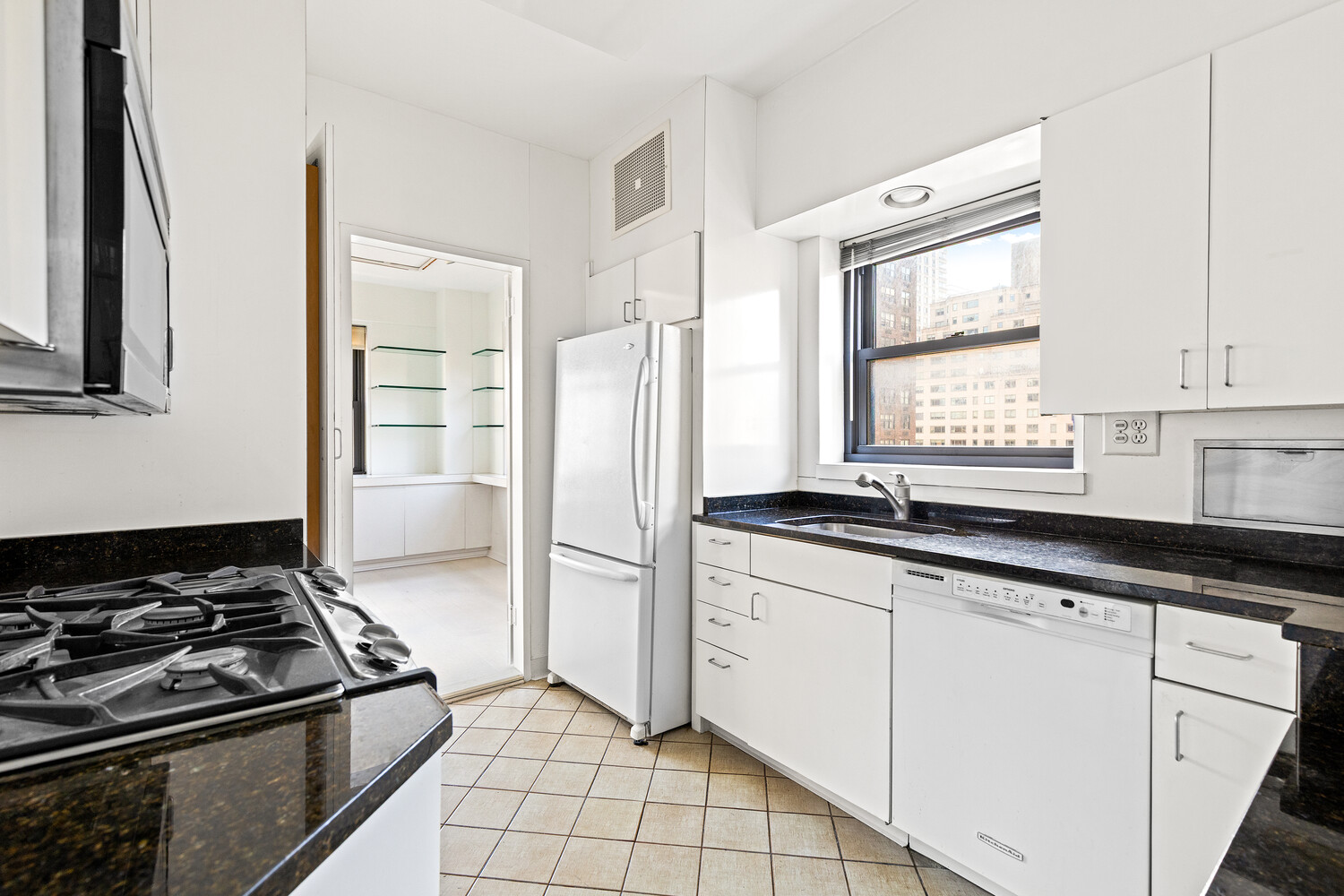 165 East 72nd Street, Unit 11C Manhattan, NY 10021 - Photo 5 of 12 a kitchen with granite countertop a sink stove and refrigerator
