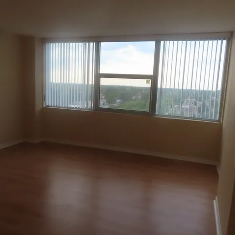a view of a hallway to an empty room with wooden floor and staircase