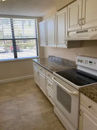 a kitchen with granite countertop white cabinets and white appliances