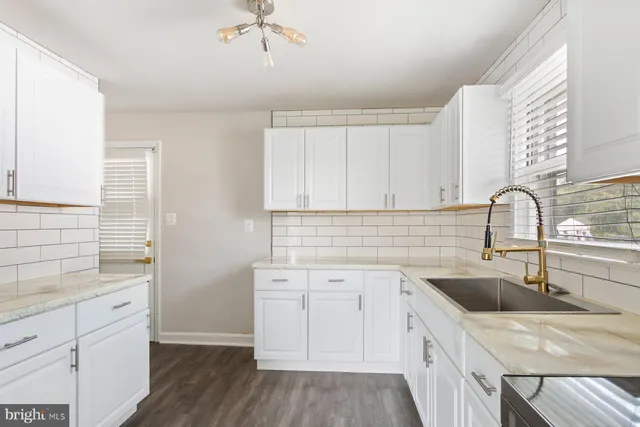 a kitchen with a sink dishwasher a stove and white cabinets with wooden floor