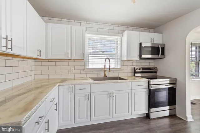 a kitchen with white cabinets sink and stainless steel appliances