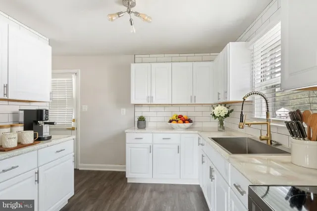 a kitchen with a sink dishwasher a stove and white cabinets with wooden floor