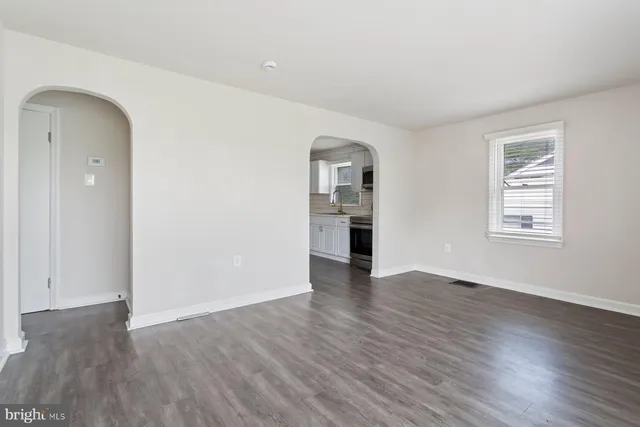 an empty room with wooden floor cabinet and windows