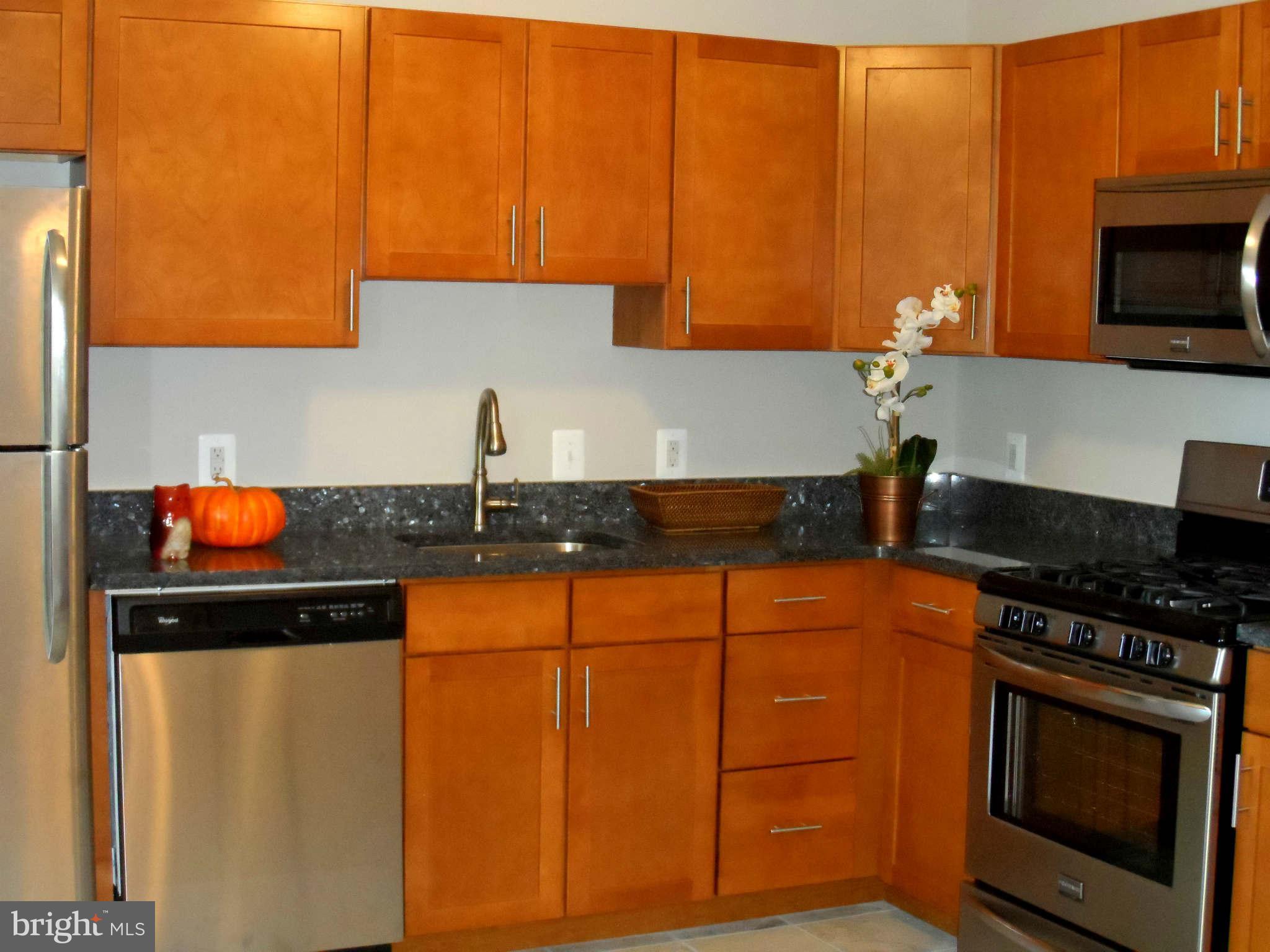 5704 Westgate Road Lanham, MD 20706 - Photo 9 of 25 a kitchen with stainless steel appliances wooden cabinets and a stove top oven