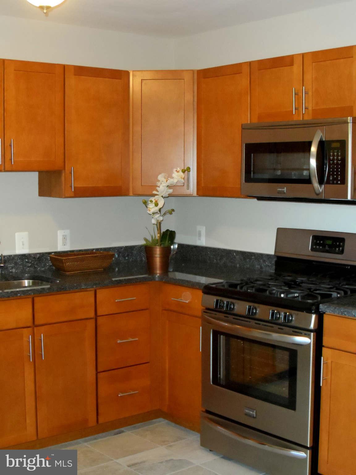 5704 Westgate Road Lanham, MD 20706 - Photo 10 of 25 a kitchen with stainless steel appliances granite countertop a stove a microwave and a sink