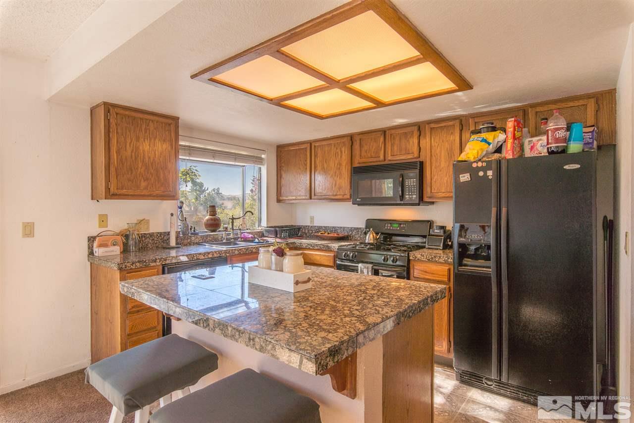 5830 Coyote Ridge Road Reno, NV 89523 - Photo 7 of 16 a kitchen with a refrigerator a stove top oven a sink and a dining table with wooden floor