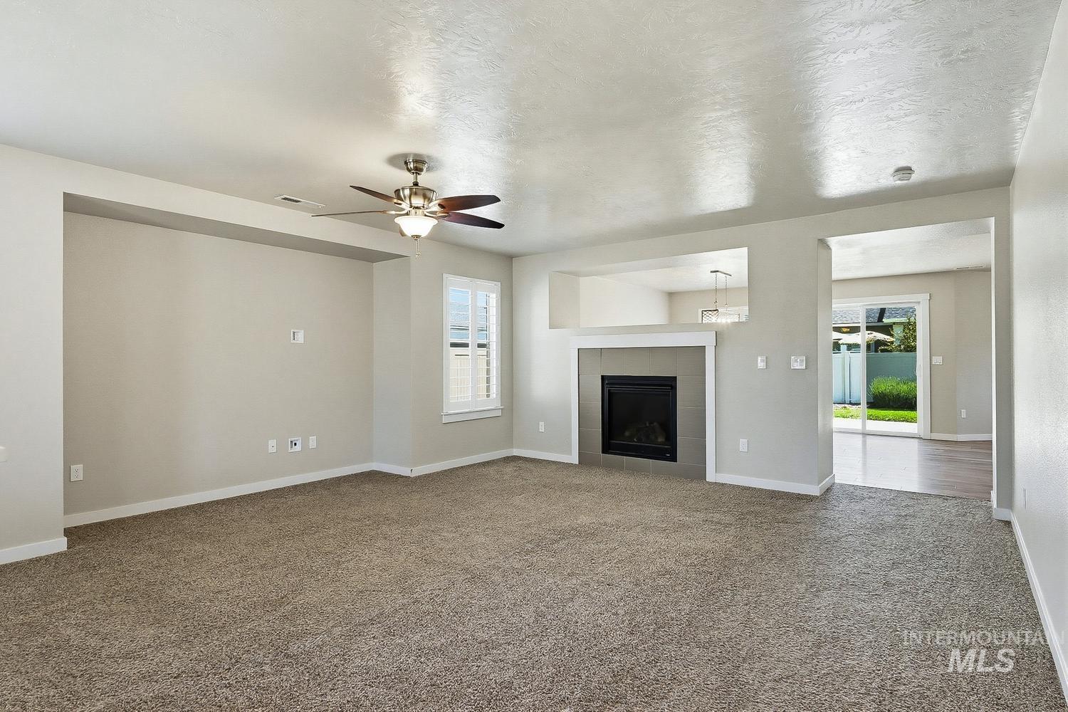 846 North Hidden View Way Star, ID 83669 - Photo 5 of 49 Spacious living area featuring carpet flooring, a ceiling fan, and a fireplace with a tile surround and mantel