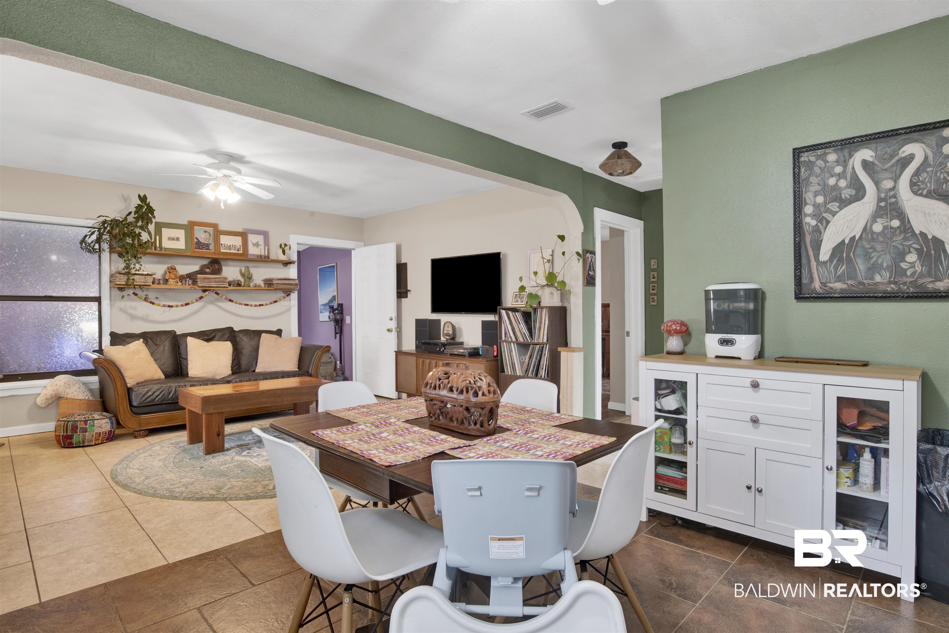 1100 North Pine Street Foley, AL 36535 - Photo 10 of 30 Open concept living and dining area featuring tile flooring, a dining table with seating for four, built-in shelving, and an archway opening