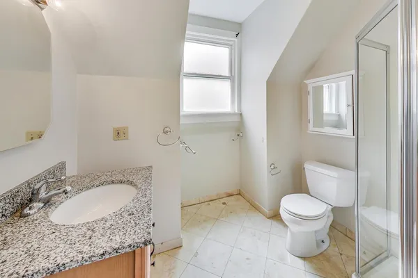 a bathroom with a granite countertop sink toilet and a mirror