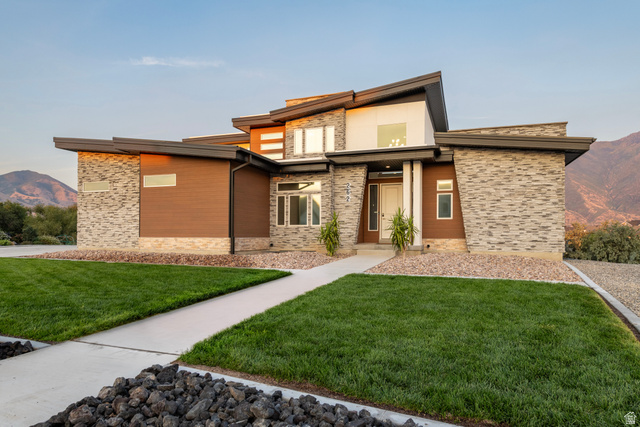 262 North Santa Fe Drive Mapleton, UT 84664 - Photo 1 of 46 Modern architectural exterior with a multi-level roofline, stone veneer and wood-finish siding, a concrete pathway, and a manicured lawn
