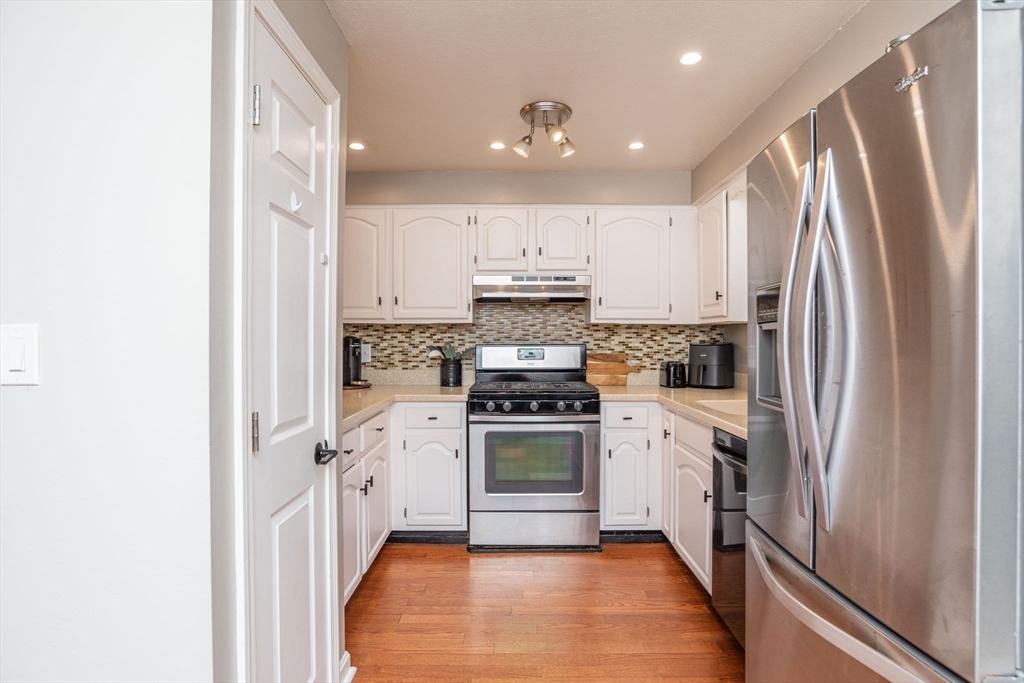 4 Colonial Drive, Unit 4 Norton, MA 02766 - Photo 22 of 34 a kitchen with stainless steel appliances granite countertop a refrigerator a stove and white cabinets with wooden floor