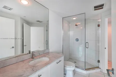 a bathroom with a granite countertop sink toilet mirror and shower
