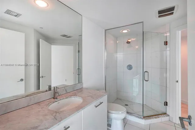 a bathroom with a granite countertop sink toilet mirror and shower