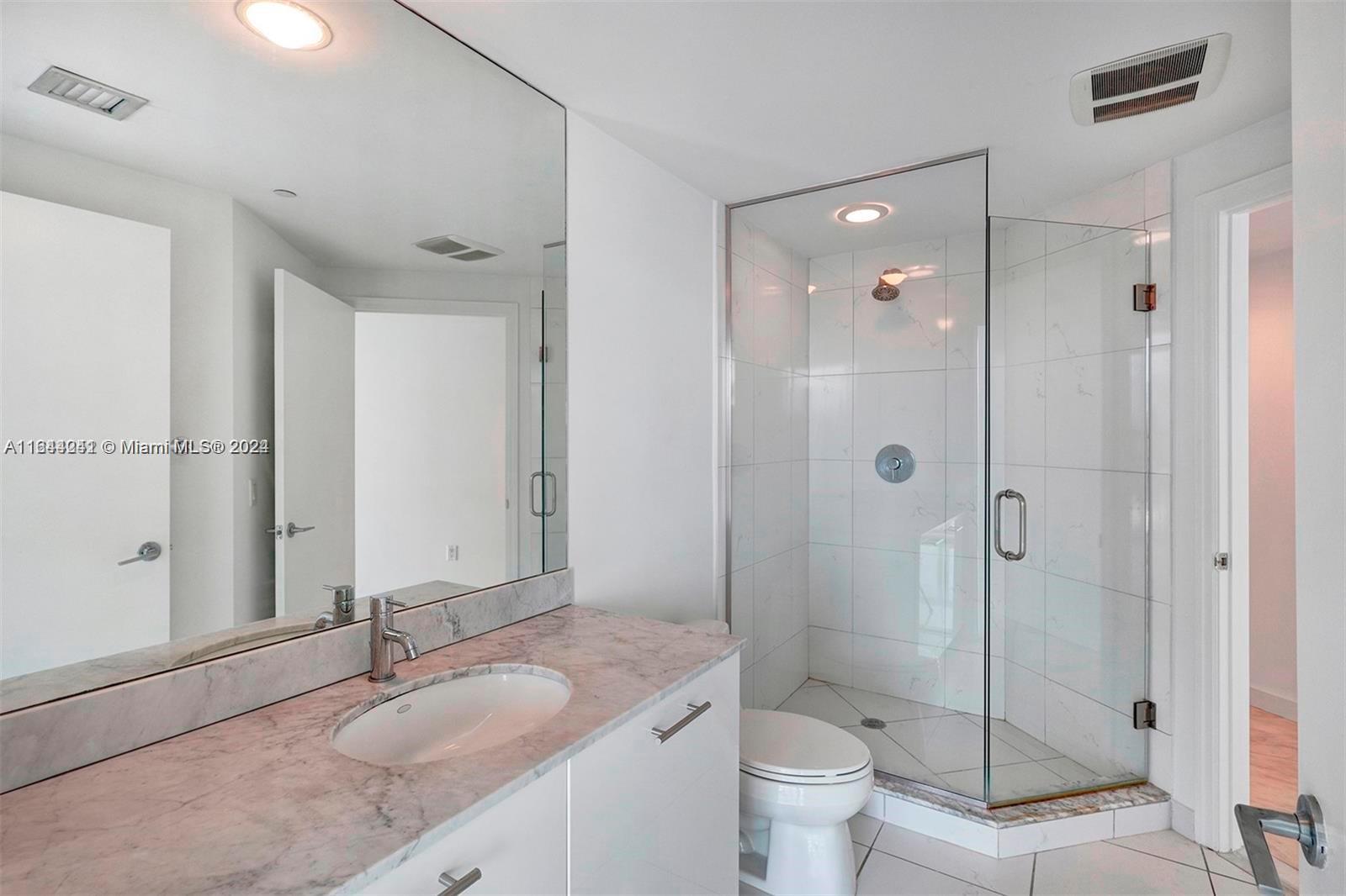 55 Southeast 6th Street, Unit 3401 Miami, FL 33131 - Photo 12 of 19 a bathroom with a granite countertop sink toilet mirror and shower