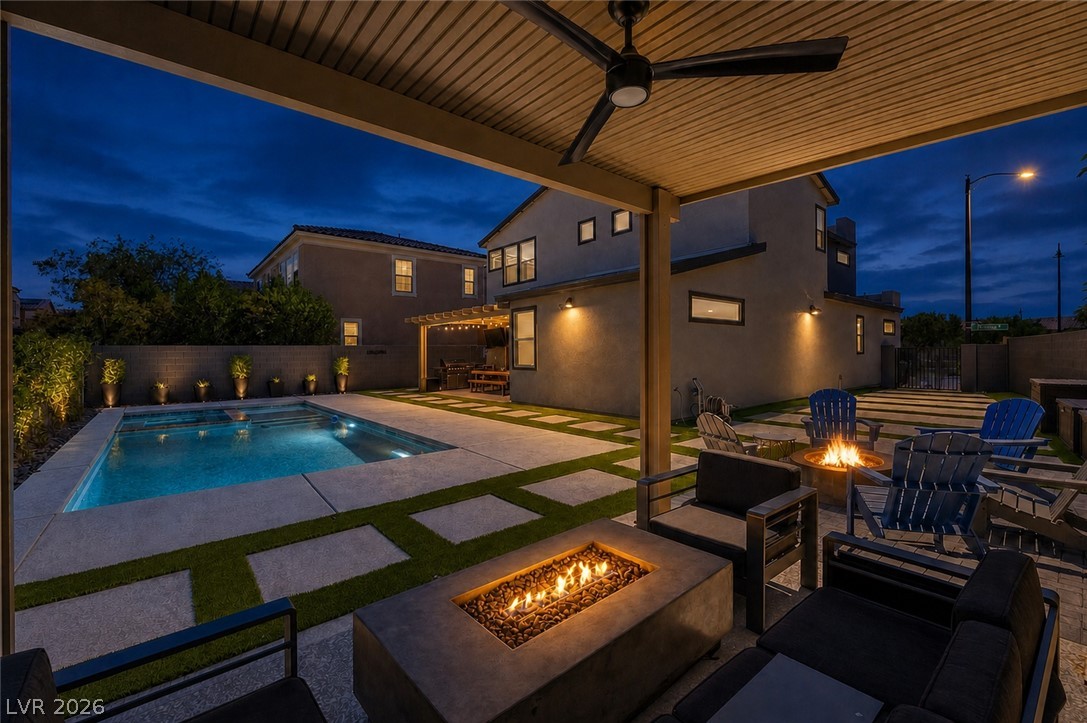 2166 Trivero Street Henderson, NV 89044 - Photo 51 of 61 An inviting backyard oasis features a shimmering pool, cozy fire pit, and ample space for entertaining under the evening sky.