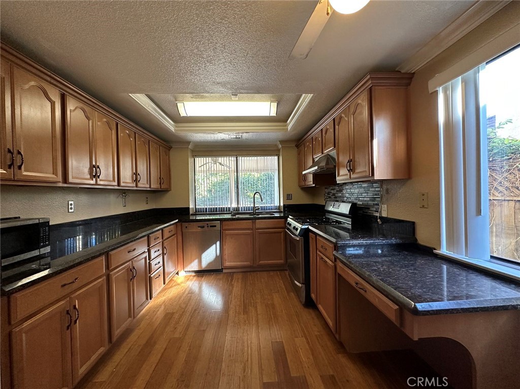 11052 Hastings Court Rancho Cucamonga, CA 91730 - Photo 3 of 14 a kitchen with kitchen island granite countertop wooden floors wooden cabinets a sink a stove and a refrigerator
