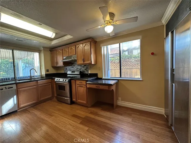 a open kitchen with granite countertop a stove top oven a sink and dishwasher with wooden floor
