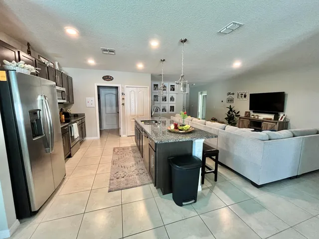 a large kitchen with stainless steel appliances kitchen island granite countertop a large stove a sink a dining table and chairs