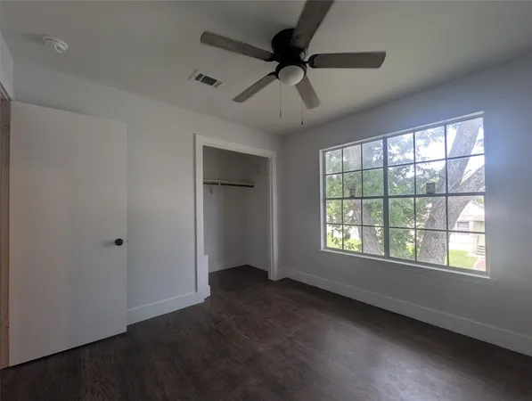a view of an empty room with a window and a ceiling fan
