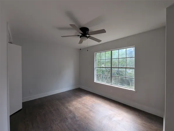 an empty room with chandelier fan and windows
