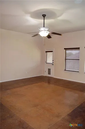 a view of an empty room with chandelier fan and fire place