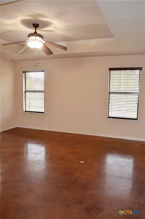 an empty room with wooden floor chandelier and windows