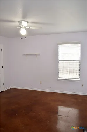 an empty room with a window and a ceiling fan
