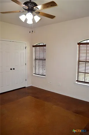 an empty room with a window and a ceiling fan