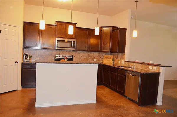 a kitchen with stainless steel appliances granite countertop a refrigerator a stove and a sink with wooden floor