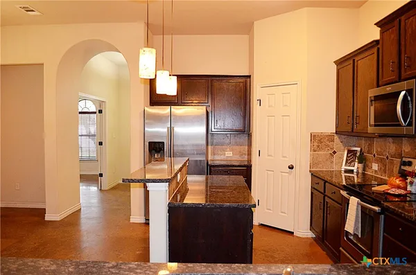 a kitchen with stainless steel appliances granite countertop a refrigerator a stove and a microwave