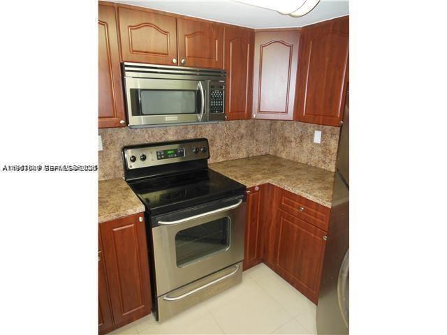 8335 Southwest 152nd Avenue, Unit B308 Miami, FL 33193 - Photo 1 of 9 a kitchen with granite countertop a stove and a microwave