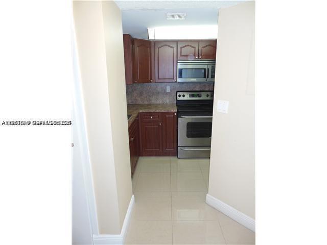 8335 Southwest 152nd Avenue, Unit B308 Miami, FL 33193 - Photo 2 of 9 a kitchen with granite countertop a refrigerator and cabinets