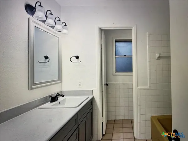 an empty room with wooden floor chandelier fan and windows