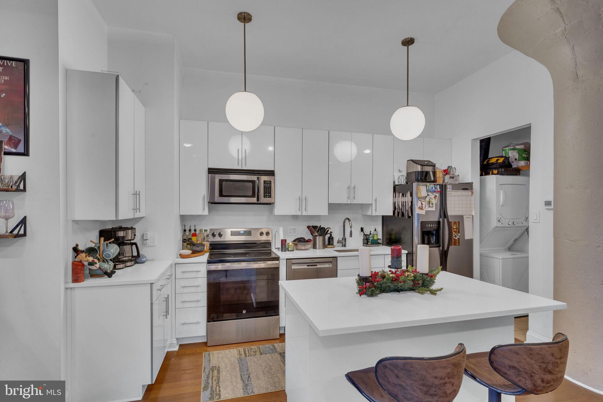 1100 South Broad Street, Unit 607B Philadelphia, PA 19146 - Photo 4 of 18 a kitchen with stainless steel appliances granite countertop a sink dishwasher a stove a refrigerator a microwave oven with white cabinets and wooden floor