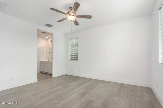 an empty room with wooden floor fan and windows