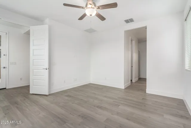 an empty room with wooden floor chandelier fan and closet area